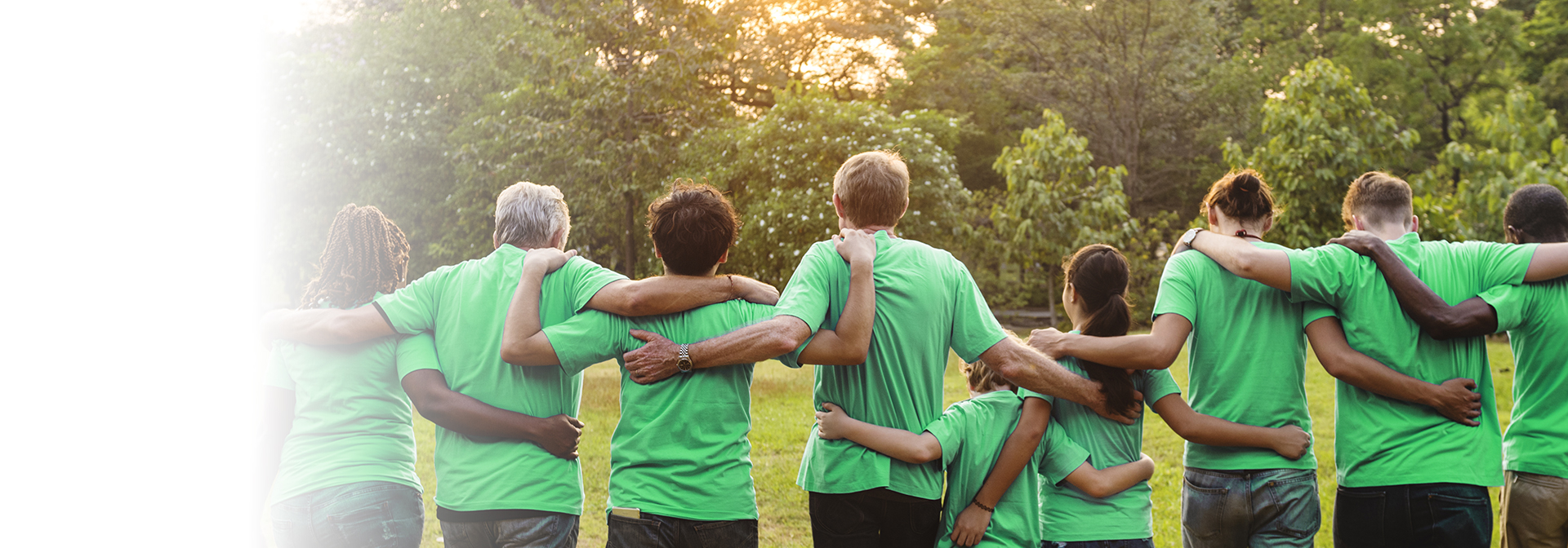 A képen zöld pólós emberek láthatók, akik átkarolják egymást