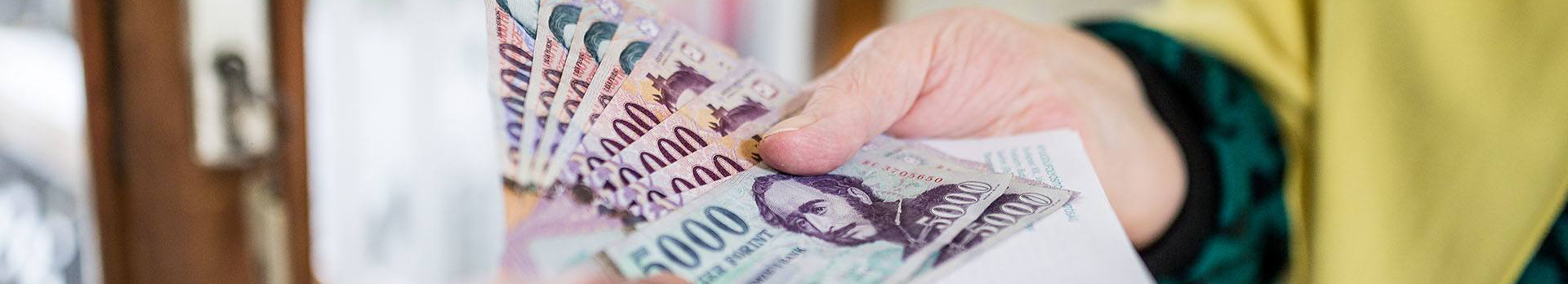 A képen egy kéz különböző címletű bankjegyeket nyújt át.