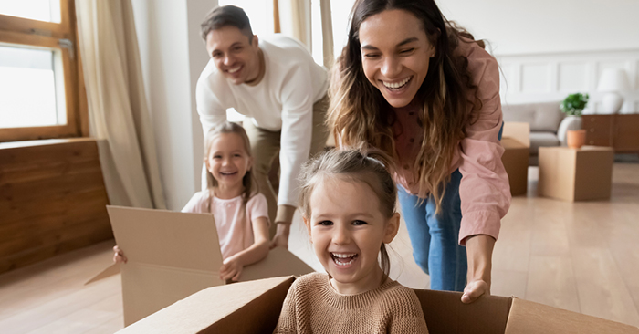 A képen szülők láthatóak akik papírdobozokban tartozkodó gyermekeikkel játszanak