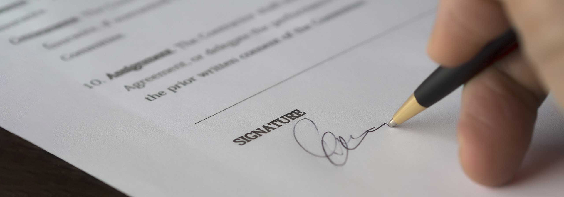 Általános szerződési feltételek. A képen egy szerződést aláíró kéz látható.